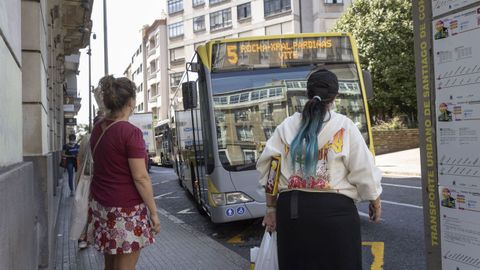 Usuarios del servicio de bus urbano de Santiago esperan en la parada de la plaza de Galicia