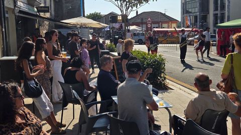 Los clientes de un bar asisten a una actuación musical en la calle