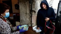 Un usuario del comedor social de Pontevedra recogiendo un t�per de comida a la puerta del convento.