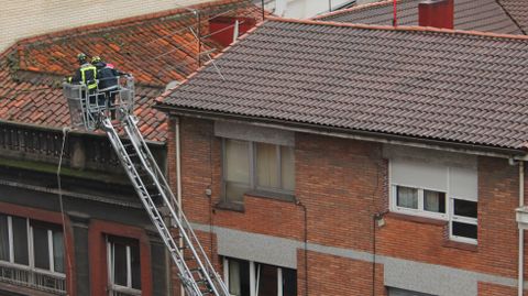 Bomberos inspeccionando un tejado tras la fuerte granizada en Gij�n