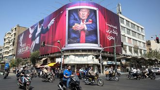 Un grupo de motoristas circulan por las proximidades de una lona contra Donald Trump, el presidente de Estados Unidos, en la capital del pa�s, Teher�n.