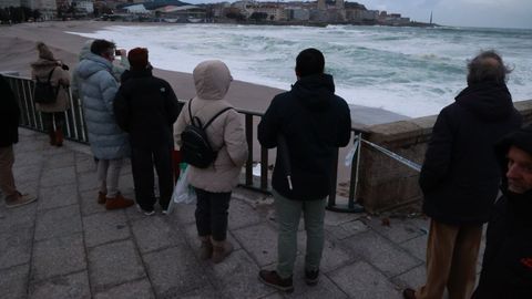 Viandantes que se acercaron hasta el paseo, sin hacer caso de los avisos y recomendaciones, para inmortalizar el oleaje