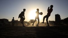 Un grupo de j�venes juegan al f�tbol al atardecer.