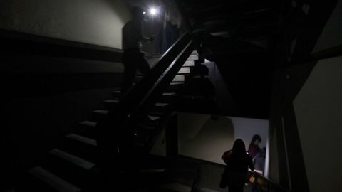 Dos personas transitan por la escalera de un edificio a oscuras de la capital venezolana