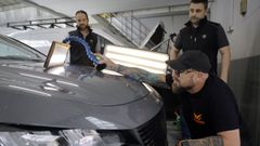 �scar Mart�nez, varillero de Madrid, ya estaba en Galicia horas antes de caer la granizada. En la imagen, repara la chapa de un coche en el concesionario Dimolk de Perillo, junto a los mec�nicos Fernando Vigo e Iv�n Lema.