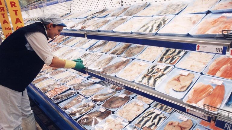 Una empleada repone bandejas en el lineal del libre servicio de pescado.