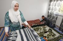Sheila y su marido, Mohammed, ayer extendiendo mantas en el sal�n donde duermen porque no pueden comprar una cama. 