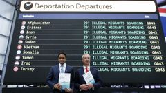 Nigel Farage  y Zia Yusuf, jefe del Departamento de Eficiencia Gubernamental de Reform UK, sostienen folletos mientras posan frente a una pantalla que muestra Salidas de Deportacin.