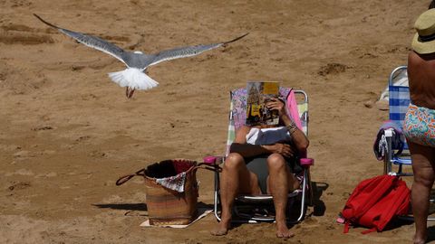 Una mujer lee en la playa en Gij�n