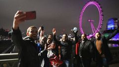 Transe�ntes se toman fotograf�as en el puente de Wensminster (Londres) para celebrar el cambio de a�o