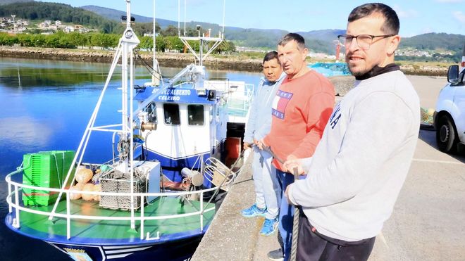 Juan Pena cos dous compañeiros de traballo na lancha de baixura no peirao de Viveiro