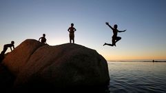 Los ni�os saltan al mar desde una roca en la playa de Camps Bay, en Ciudad del Cabo (Sud�firca).