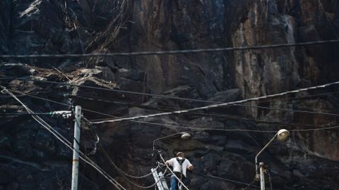 Un hombre trabaja en el tendido el�ctrico da�ado por el fuego en Funchal, la capital de Madeira