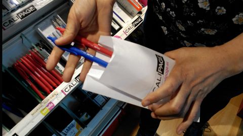 La dependienta de una papeler�a introduce unos bol�grafos en un sobre de papel