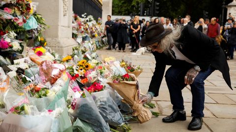 Un hombre coloca su tributo floral ante el palacio de Buckingham.