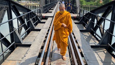 Un budista cruza el puente de un tren en Thailandia