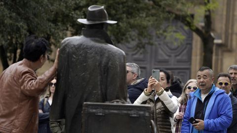  Unos turistas asiticos se fotografan con la estatua de El regreso de Williams B. Arrensberg en la plaza Porlier, en Oviedo