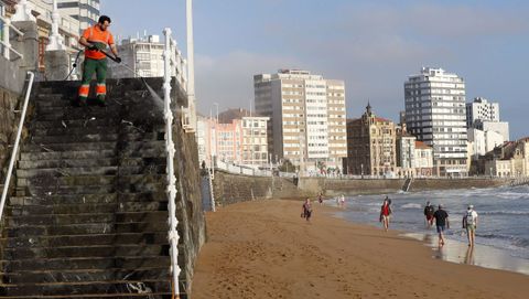 Un operario limpia una de las escaleras de acceso a la playa de San Lorenzo de Gij�n