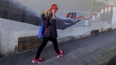Una mujer pasa por delante de un mural en Siero