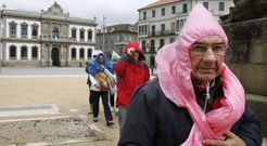 Unos turistas, ayer, protegi�ndose de la lluvia con los medios que ten�an a mano mientras atravesaban la plaza de Espa�a. 