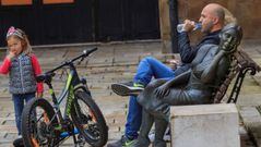 Una hombre descansa en un banco despu�s de un paseo en bici con su hija en la plaza Trascorrales de Oviedo