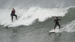 Dos surfistas desafan el temporal en la playa de San Lorenzo, en Gijn
