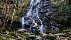 O mestre gaiteiro, artesán, investigador e coleccionista moañés Xavier Blanco toca unha gaita de cana ao pé da fervenza do Fócaro, na aldea da Seara, onde estará a sede da súa fundación.