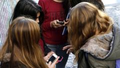 Estudiantes de la ESO utilizan sus teléfonos móviles a la salida de un instituto en Vigo, en una imagen de archivo.