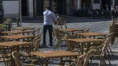 Un camarero recoge las sillas de una terraza en Santiago de Compostela.