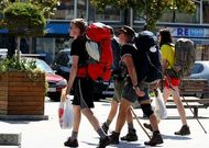 Cuatro peregrinos cruzan la Praza 8 de Marzo de Cee en su caminata hacia Fisterra. 
