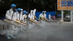 Miembros del equipo de limpieza de Pek�n desinfectan un mercado mayorista de la capital china