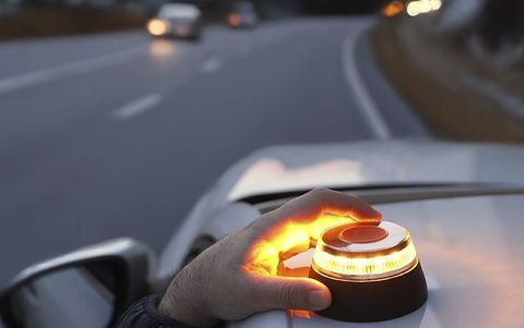 Un conductor activa la baliza V-16 sobre el techo de su coche.