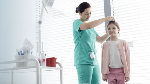 Una pediatra toma la altura de una ni�a en la consulta.