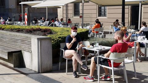 Clientes con mascarilla en una terraza de Gijn