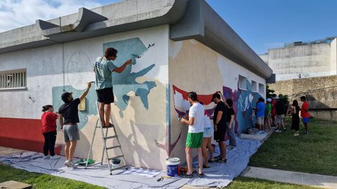 Usuarios y voluntarios de Cruz Roja pintando el mural.