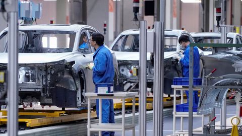 Dos trabajadores de SAIC, la compa��a china que crear� una planta de coches MG en Ferrol, en una l�nea de ensamblaje de veh�culos el�ctricos en Shangh�i.