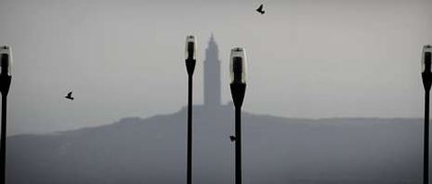 Varios p�jaros vuelan entre las farolas del Monte de San Pedro con la torre de H�rcules al fondo. 