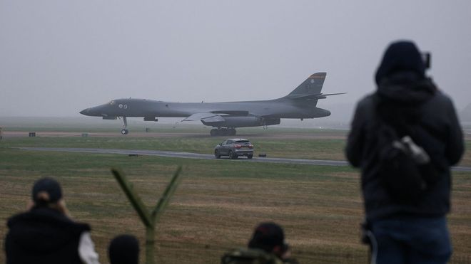 Curiosos observan desde el exterior el bombardero estadounidense que aterriz&oacute; ayer en la base de Fairford de Reino Unido. 