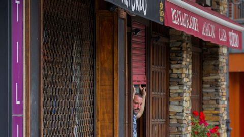 Un hostelero de Oviedo entra en su local para prepararlo ante la posibilidad de apertura.