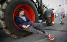 Un ganadero acostado sobre la rueda de su tractor a las puertas del aparcamiento del Lidl. 