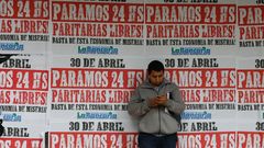  Un hombre mira un tel�fono en un muro con carteles que llaman a la huelga general
