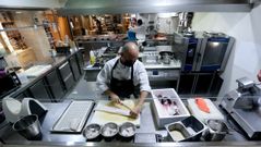 La cocina de Culuca (A Coru�a), el s�bado por la ma�ana. Chisco Jim�nez, propietario del local, corta pescado mientras dos trabajadores preparan envases y ultiman los detalles de las placas de callos