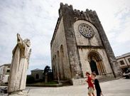 Peregrinas pasan ante la iglesia de San Nicol�s, en Portomar�n, cerrada el pasado martes santo.