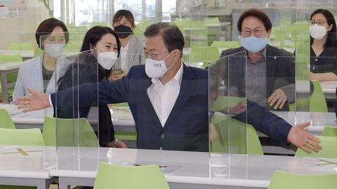 El presidente de Corea del Sur, Moon Jae-in, extiende los brazos para medir la distancia entre los asientos en la cafetera de una escuela de Sel. Los colegios reabrirn la prxima semana