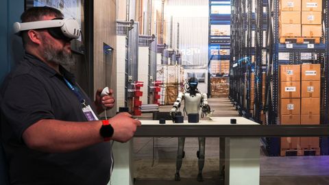 Un hombre dirige aun robot trabajando en un almac&eacute;n en el Mobile World Congress de Barcelona