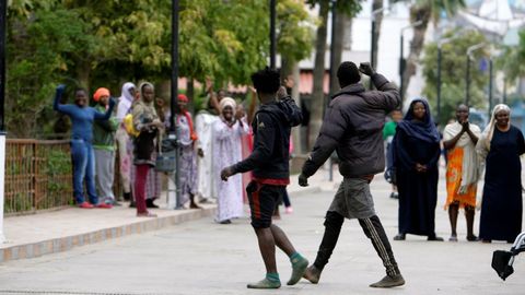 Dos de los 52 inmigrantes que accedieron este domingo a Melilla saltando la valla son felicitados por otros subsaharianos.