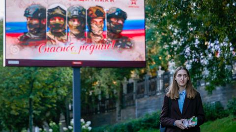 La candidata de Yabloko Polina Lermant reparte propaganda electoral en una calle de Mosc�, junto a un cartel de propaganda patri�tica sobre la guerra de Ucrania