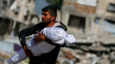 Un padre palestino lleva el cadver de su hijo, asesinado por bombardeos israeles, en Yabalia.