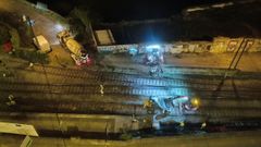 Los obreros derribando un muro de madrugada junto a la v�a del tren de Lugo