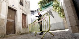 Uno de los afectados se�ala las grietas en un muro junto a las vallas colocadas por el Concello. 